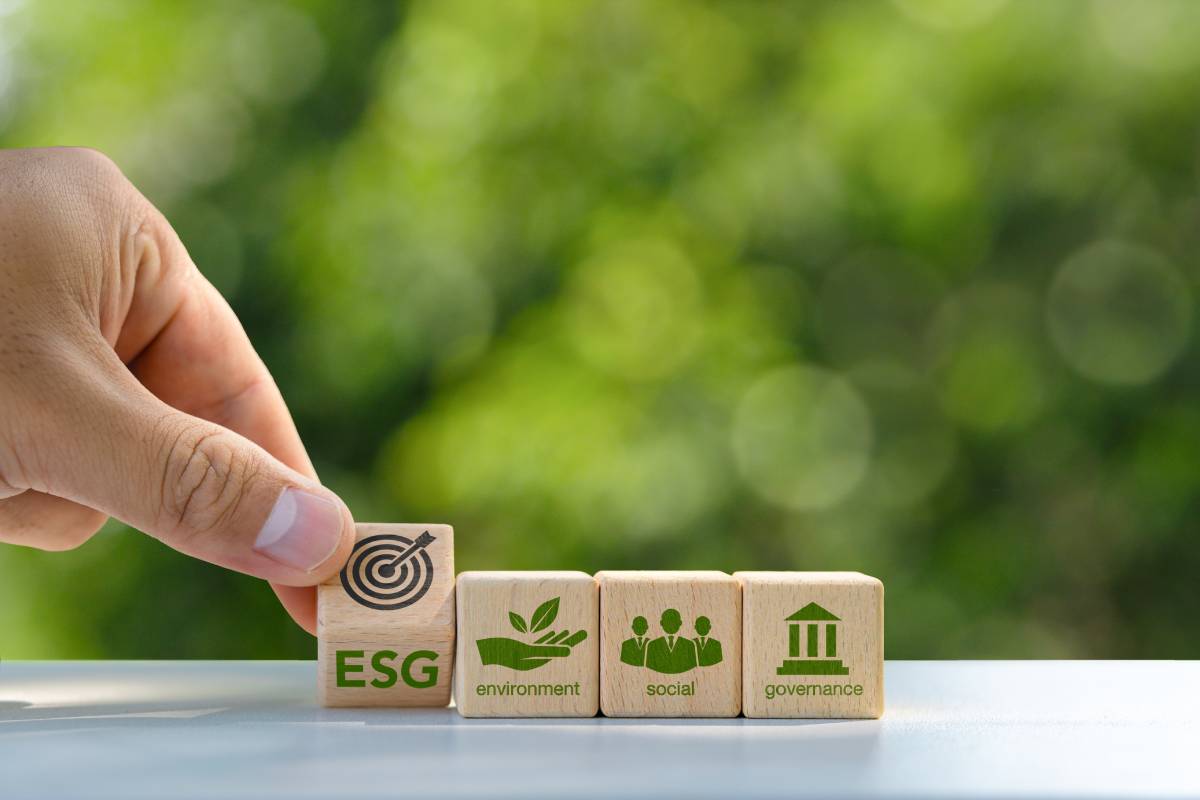 ESG concept of environmental, social and governance. Sustainable corporation development. A hand flips a wooden block with the abbreviation ESG onto the target icon. on a green background..